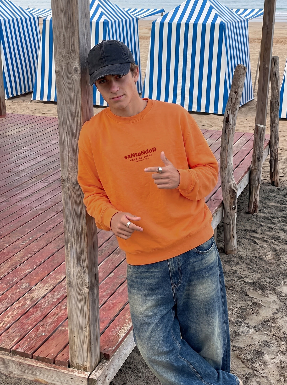 Sudadera coral «Santander» de Cero de Costa con vaqueros anchos junto a las casetas de El Sardinero