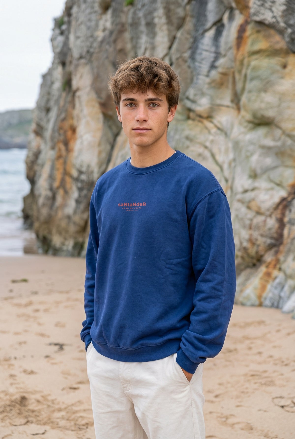 Sudadera azul «Santander» de Cero de Costa con estampado rojo, vista de frente en la playa